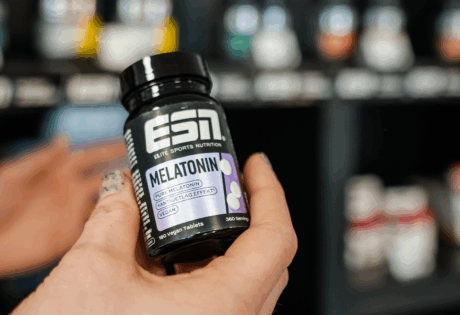 a hand holding a bottle of vitamins from esn.