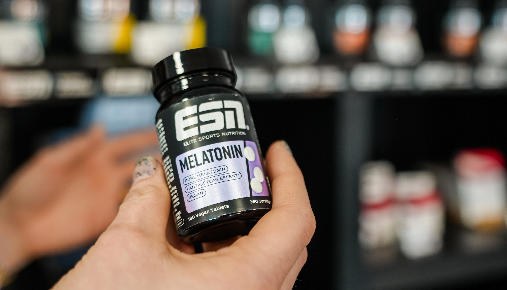 a hand holding a bottle of vitamins from esn.